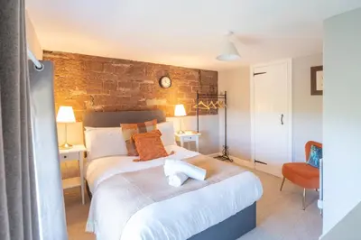 a bedroom with a large bed with a brick wall at Gatesgarth Cottage @ The Pheasant Inn in Brampton