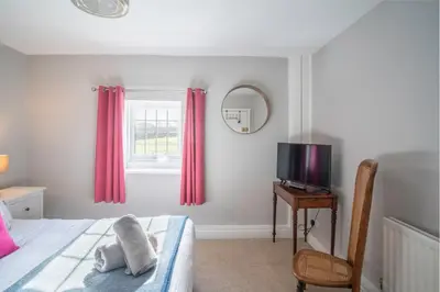 a bedroom with a bed with red curtains and a television at Gatesgarth Cottage @ The Pheasant Inn in Brampton