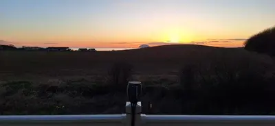 a sunset over a field with a parking meter at Carnoustie 24 - Turnberry Holiday Park - short walk to beach in Girvan