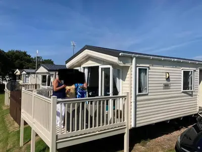 a woman standing on the porch of a mobile home at Carnoustie 24 - Turnberry Holiday Park - short walk to beach in Girvan