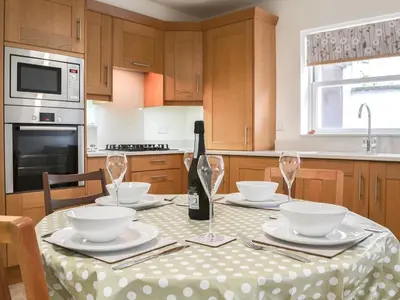 a kitchen with a table with a bottle of wine at Six The Hollies in Keswick