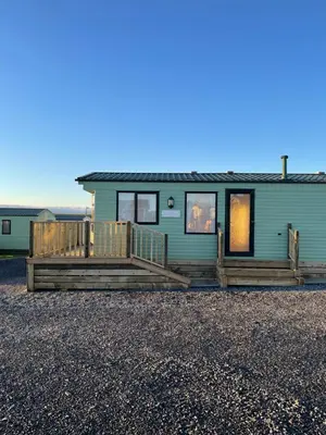 a green house with a large porch and a deck at Beautiful 2-Bed Static caravan in Newton Stewart