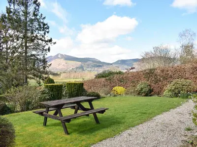 a picnic table in the grass with mountains in the background at Littlethwaite in Keswick