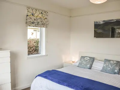 a white bedroom with a bed and a window at Littlethwaite in Keswick