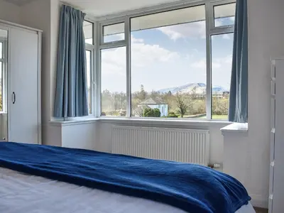 a bedroom with a blue bed and a large window at Littlethwaite in Keswick