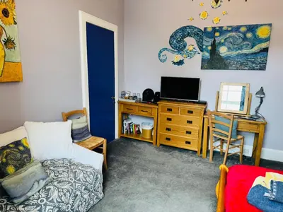 a living room with a bed and a desk with a television at The Art Bank in Dalbeattie