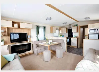 a living room with a couch and a table and a kitchen at AJL Caravan Rentals in Turnberry