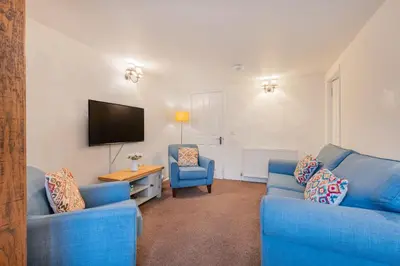 a living room with two blue couches and a television at Cottage 2, Old Farmhouse Mews in Braithwaite