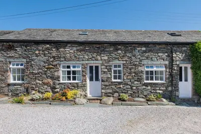 a stone cottage with white doors and windows at Cottage 2, Old Farmhouse Mews in Braithwaite