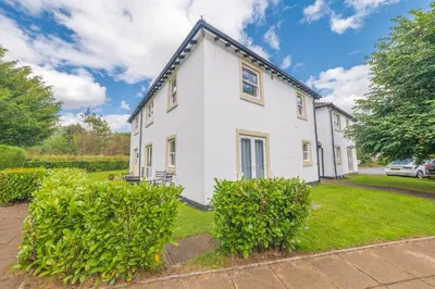 a white house with bushes in front of it at Derwent Cottage in Keswick