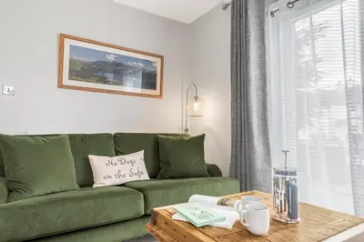 a living room with a green couch and a coffee table at Derwent Cottage in Keswick