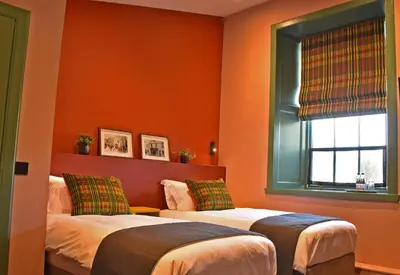 two beds in a room with orange walls at Masonic Arms Gatehouse in Gatehouse of Fleet