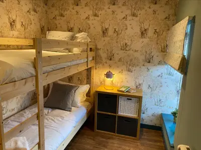 a bedroom with two bunk beds and a table with a lamp at Masonic Arms Gatehouse in Gatehouse of Fleet