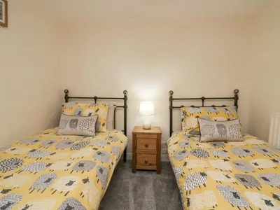 a bedroom with two beds and a night stand at Nook Cottage in Keswick