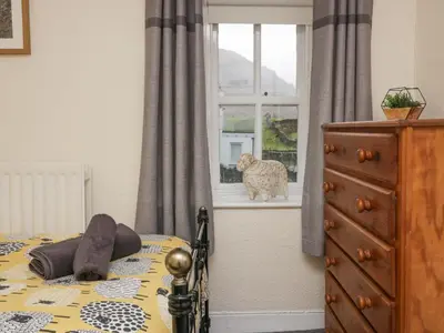 a bedroom with a bed and a dog looking out the window at Nook Cottage in Keswick