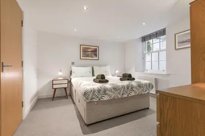 a white bedroom with a bed and a table at Chaucer's Retreat, Chaucer House, Keswick in Keswick