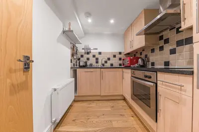a kitchen with wooden cabinets and a stove top oven at Chaucer's Retreat, Chaucer House, Keswick in Keswick