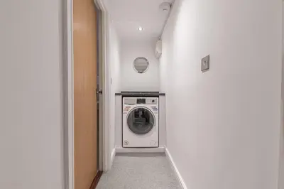 a laundry room with a washing machine in a hallway at Chaucer's Retreat, Chaucer House, Keswick in Keswick