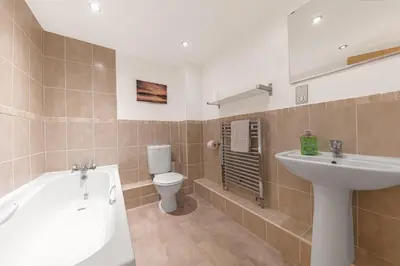 a bathroom with a sink and a tub and a toilet at Chaucer's Retreat, Chaucer House, Keswick in Keswick