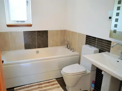 a bathroom with a tub and a toilet and a sink at Annapurna in Portpatrick