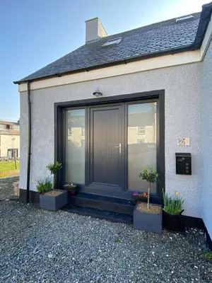 a house with a black door and two potted plants at Islecroft House Bed & Breakfast in Isle of Whithorn