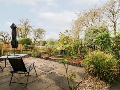 a patio with a table and chairs in a garden at Noble Knott in Keswick