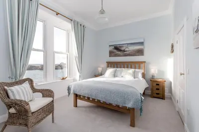 a bedroom with a bed and a chair and a window at Carlton House Portpatrick in Portpatrick