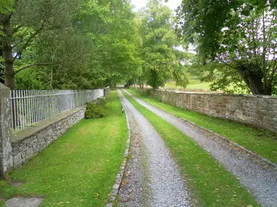 a gravel road next to a stone wall at Fiddleback Farm in Wigton