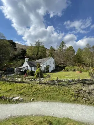 a white house on the side of a hill at Brandlehow HOT TUB HIRE AVAILABLE in Portinscale