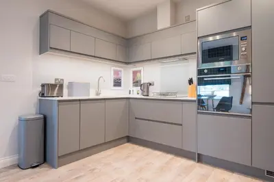 a kitchen with white cabinets and a sink at Howe Keld 3 Ground floor in Keswick