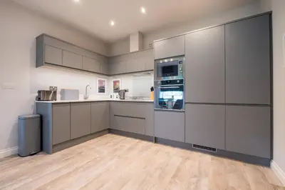 a large kitchen with white cabinets and appliances at Howe Keld 3 Ground floor in Keswick