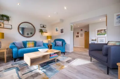 a living room with blue furniture and a mirror at Howe Keld 3 Ground floor in Keswick