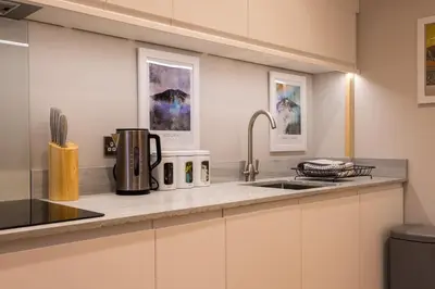 a kitchen with white cabinets and a sink at Howe Keld 2 Ground Floor in Keswick