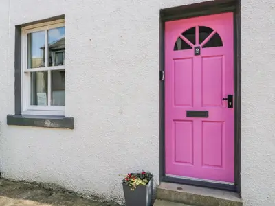 a pink door on a white building with a window at No 2 Waterloo Street in Cockermouth