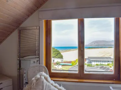a bedroom with a window with a view of the beach at Seal Rocks in Lendalfoot