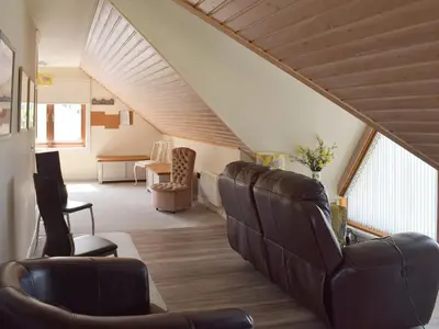 a living room with leather chairs and a staircase at Seal Rocks in Lendalfoot