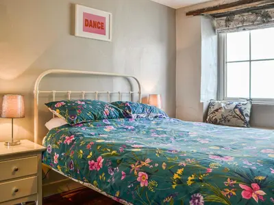 a bedroom with a bed with a floral bedspread at Pollywiggle Cottage in Keswick