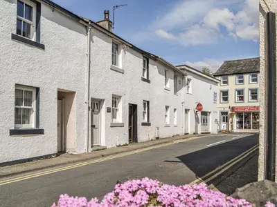 an empty street with white houses and pink flowers at Pollywiggle Cottage in Keswick