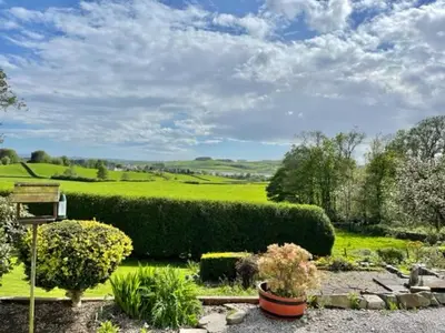 a garden with bushes and flowers on a green field at AIRDSIDE COTTAGE in Castle Douglas