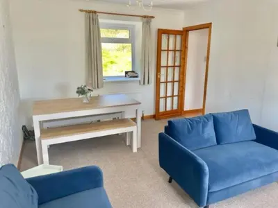 a living room with a blue couch and a table at AIRDSIDE COTTAGE in Castle Douglas