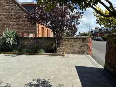 a brick wall next to a street with a building at Willowbank in Ayr