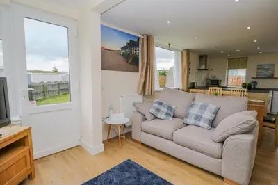 a living room with a couch and a kitchen at The Wigwam in Dumfries