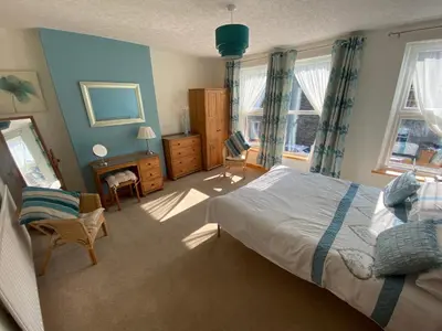 a bedroom with a bed and a chair and windows at Felltop Cottage in Keswick