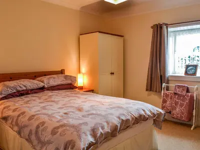 a bedroom with a bed and a cabinet and a window at Auld Dairy Cottage in Drummore