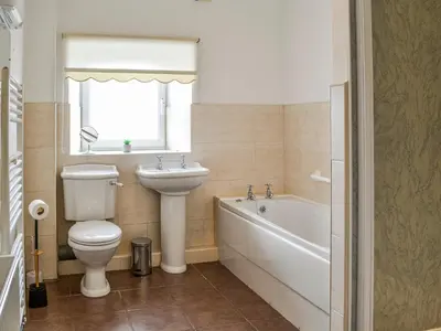 a bathroom with a toilet and a sink and a bath tub at Auld Dairy Cottage in Drummore