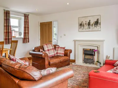 a living room with leather furniture and a fireplace at Mount Farm - The Stable in Harker