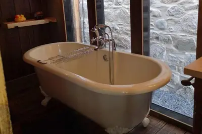a bath tub in a room with a stone wall at 1 Bed Cabin in the Magical Galloway Forest Park in Newton Stewart
