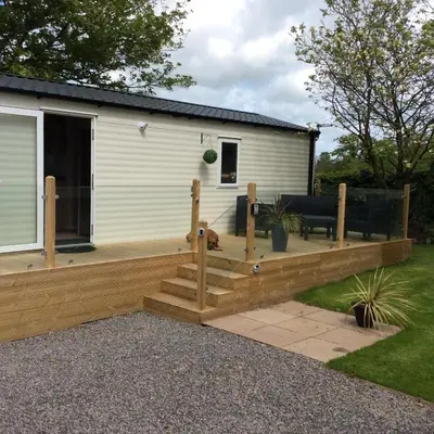 a wooden deck with a bench and a house at Lake District Western 2-Bed Cabin Pet Friendly in Wigton