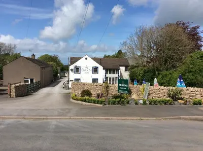 a white house with a stone fence in front of it at Lake District Western 2-Bed Cabin Pet Friendly in Wigton