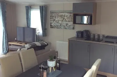 a kitchen and a living room with a table and a couch at Lake District Western 2-Bed Cabin Pet Friendly in Wigton